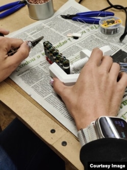 A woman in a Lviv workshop taping vape batteries sent from Leeds into a stack that will be placed into a powerbank.