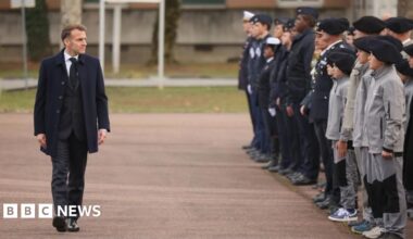French President Emmanuel Macron reviews troops and students of an army high school prior to his speech to unveil a new national military service plan at the military base in Varces