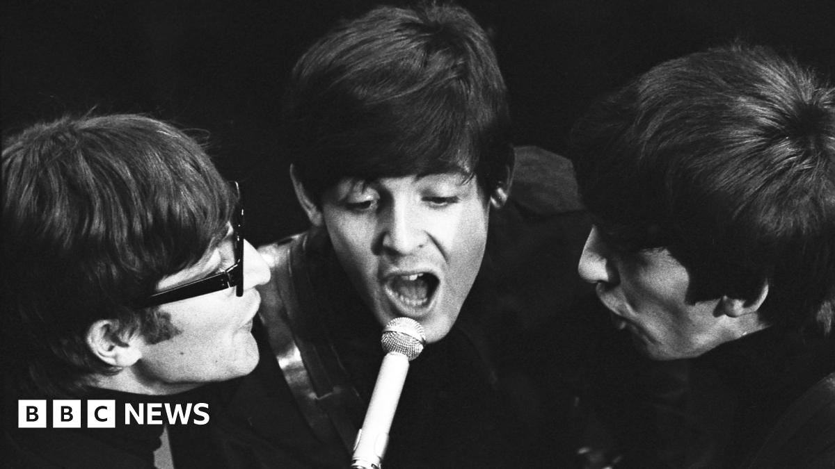 Young 18 year old man sits in the passenger seat of a black VW car, his arm resting on the open window as he looks to camera