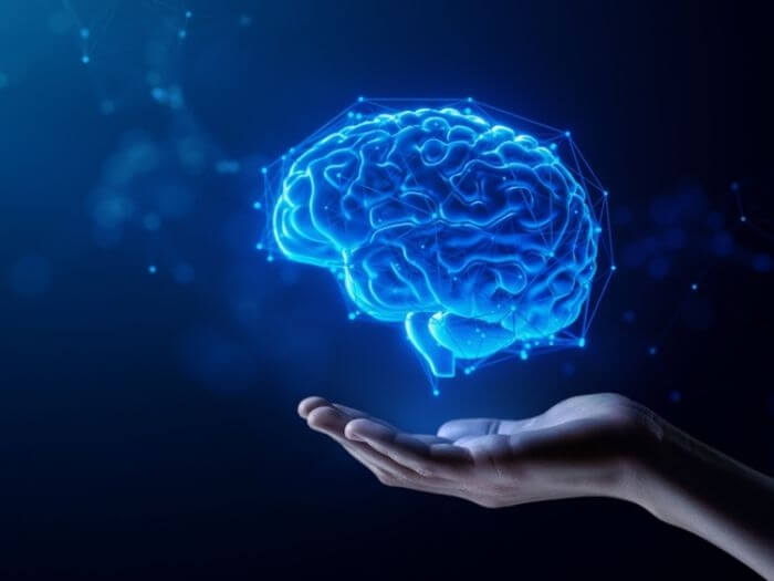 An outstretched hand underneath an artificial brain surrounded by blue digital neural points, representing the concept of AI.