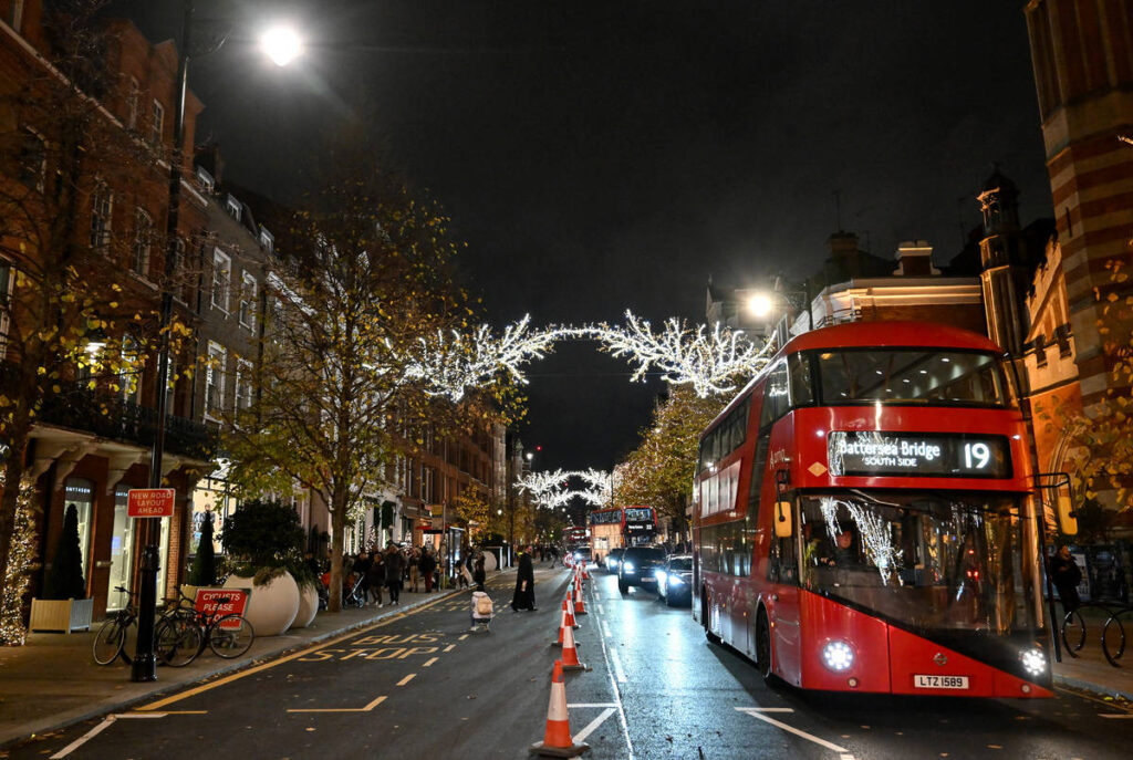 christmas lights shining over chelsea, glowing above traffic passing in the street underneath