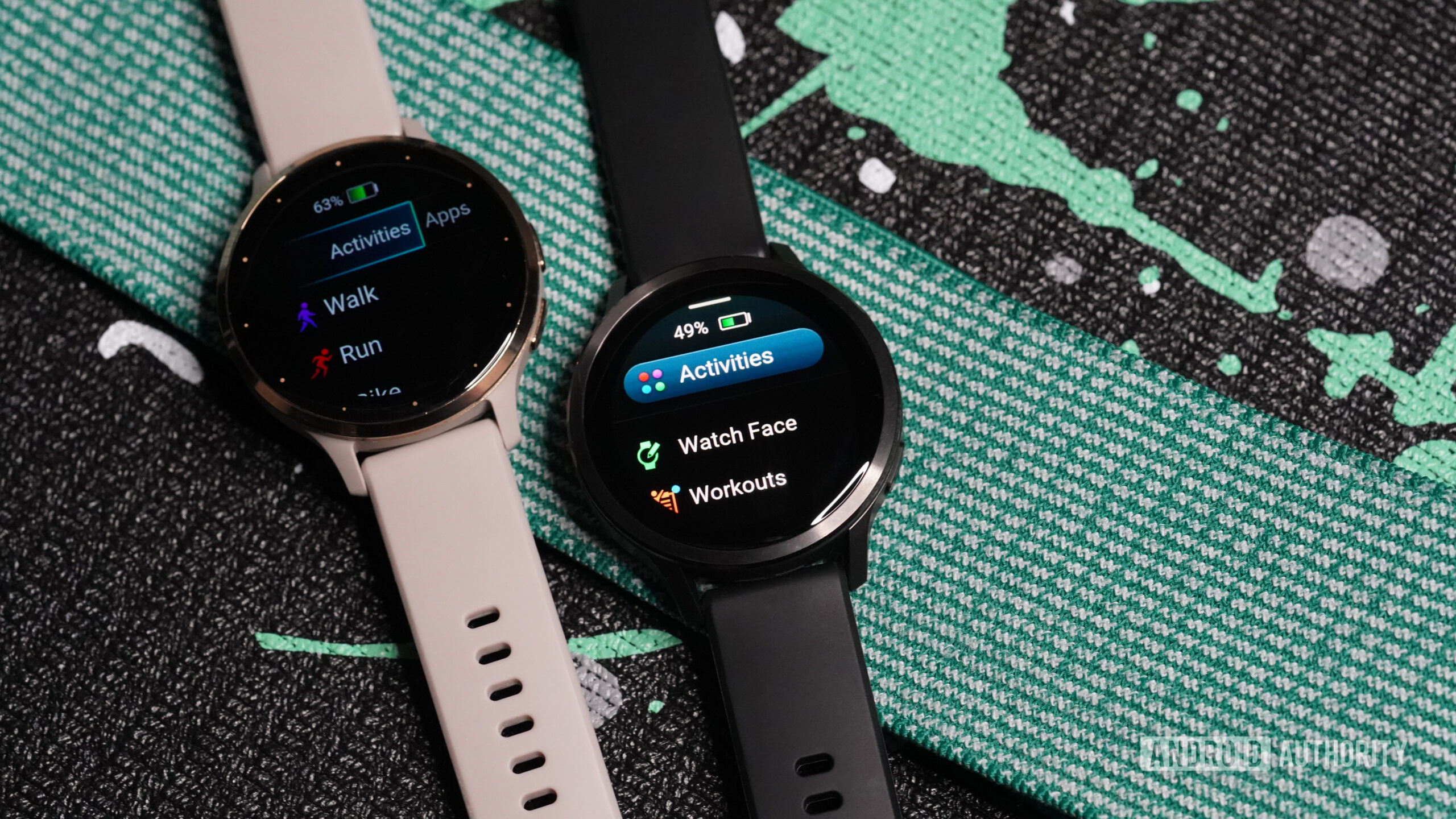 A Garmin Venu 4 rests alongside a Venu 3, each displaying menu screens.