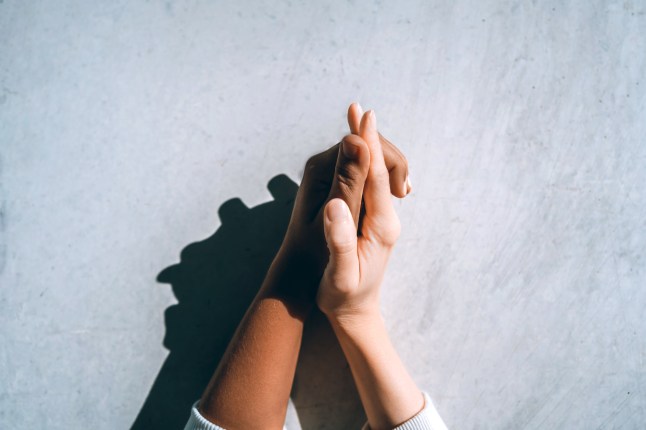 Symbol of international couples holding hands against a concrete gray wall