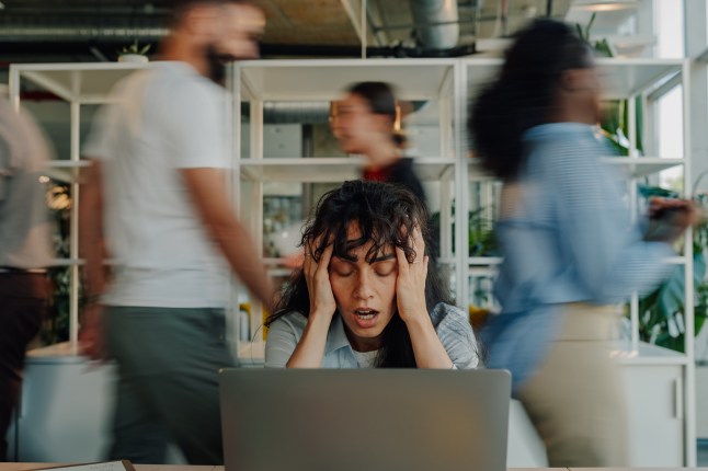 Stressed businesswoman holding head in busy office