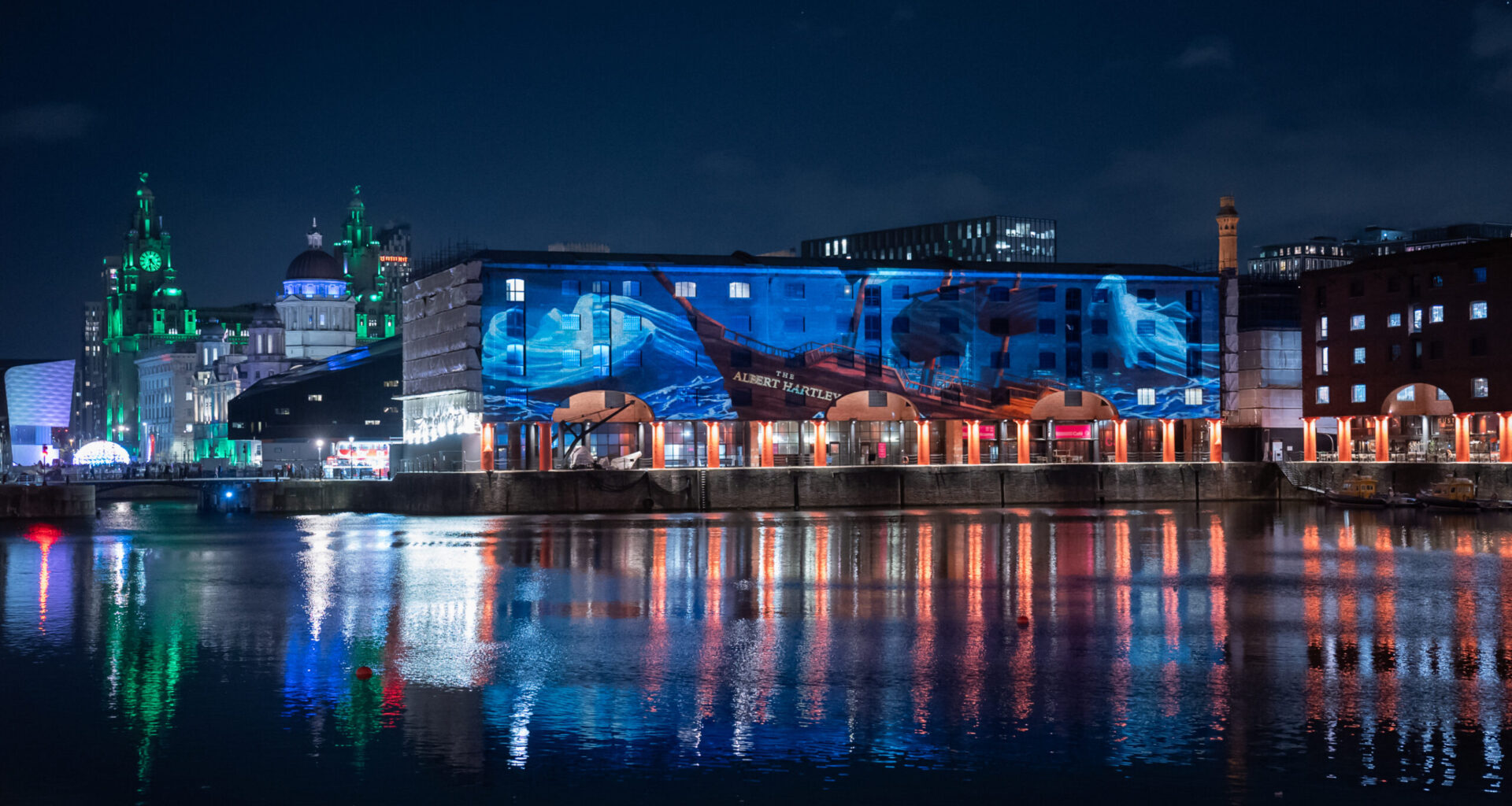 The Royal Albert Dock with a large scale halloween projection on the buildings at night time.