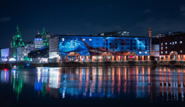 The Royal Albert Dock with a large scale halloween projection on the buildings at night time.