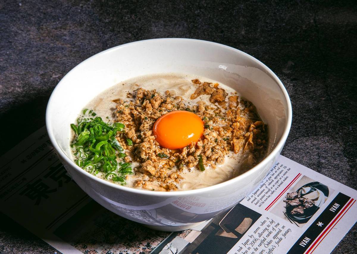 a bowl of ramen topped with mince chicken and an egg yolk