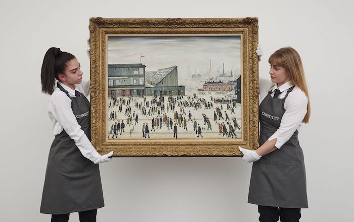 LS Lowry's iconic 'Going to the Match' painting being held by two careful art centre staff wearing white gloves