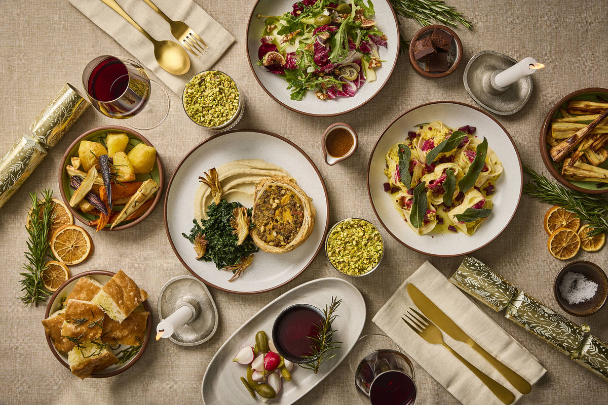 six courses of festive vegan food all arranged on a table at once, ranging from salads to tarts, pasta, and more