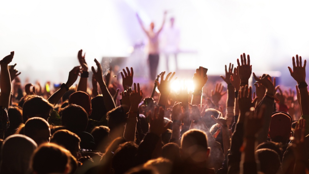 People in the audience holding their hands in the air during a concert.