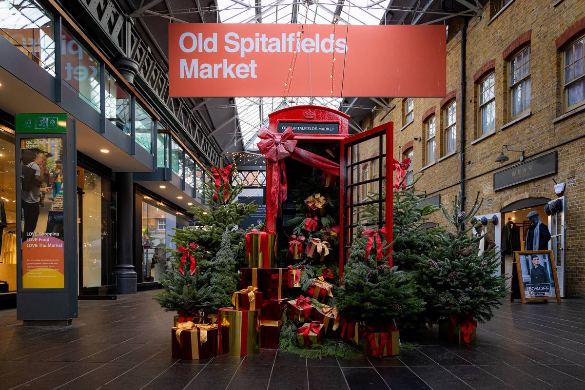 a christmassy display showing presents and christmas trees spilling out of and surrounding a red phone box in old spitalfields market