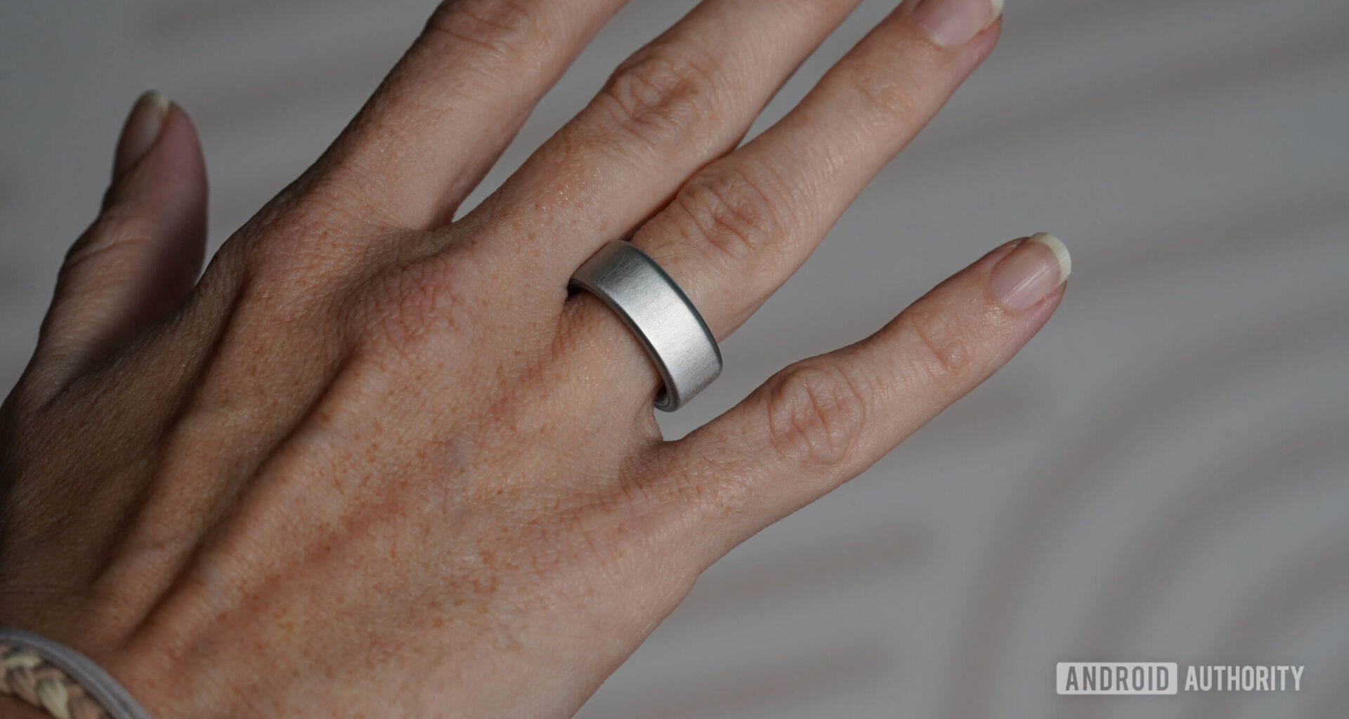 A user models their stilver Oura Ring 4.