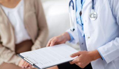 doctor holding a report with patient in the background