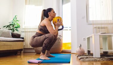 woman in a deep squat holding a yellow kettlebell at her chest, on a blue exercise mat in a living room setting.
