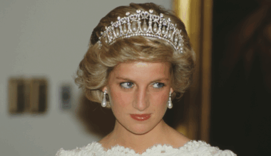 A headshot of Princess Diana wearing a tiara and pearl earrings with a white lace dress