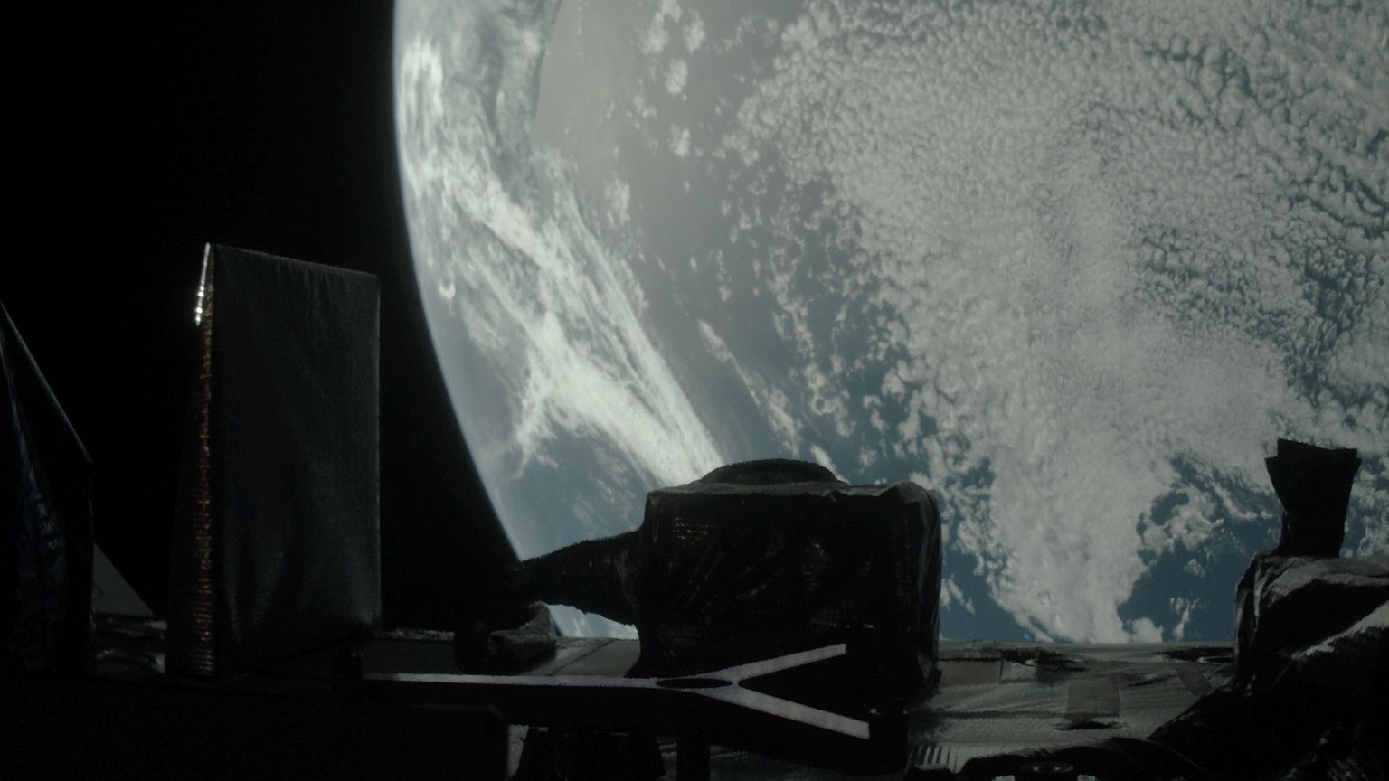 spacecraft photo of earth, with parts of the probe visible in the foreground