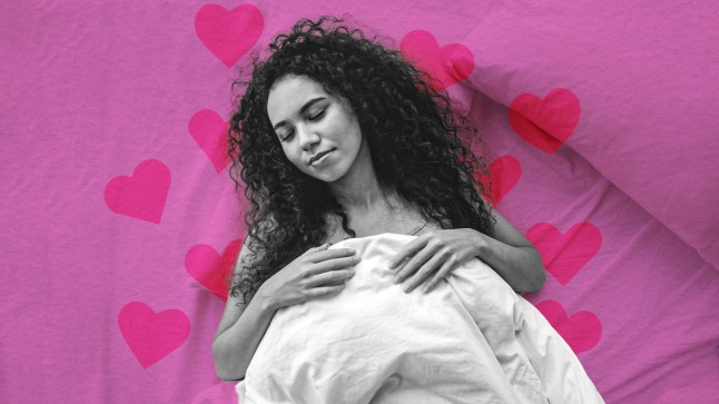 A woman lies in bed under white sheets against a background of pink hearts.