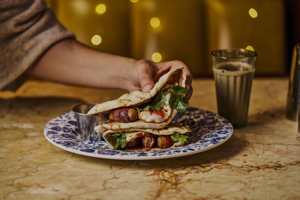 a hand holding a festive special Naan Roll at Dishoom created by Seema Pankhania