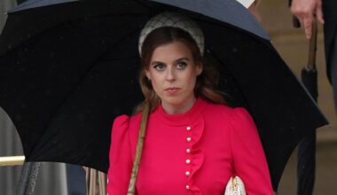 Princess Beatrice wears a red dress and carries a black umbrella while walking in front of sister Princess Eugenie at the Sovereign&#039;s Garden Party at Buckingham Palace on May 21, 2024
