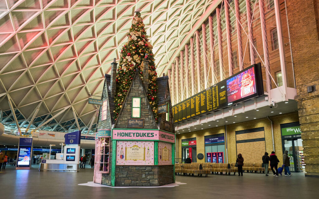 a harry potter christmas tree standing tall in the middle of king's cross station