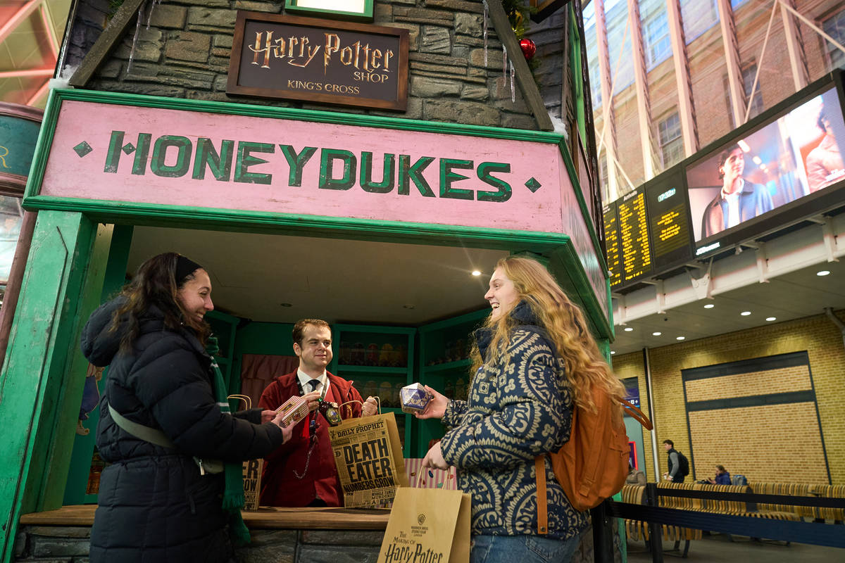 a harry potter themed honeydukes store, with two people purchasing candy from someone behind the counter