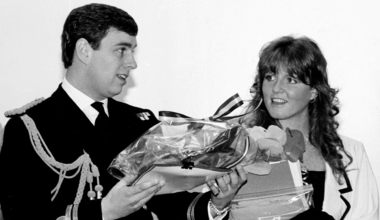 Prince Andrew wearing a naval uniform holding gifts smiling next to Sarah Ferguson