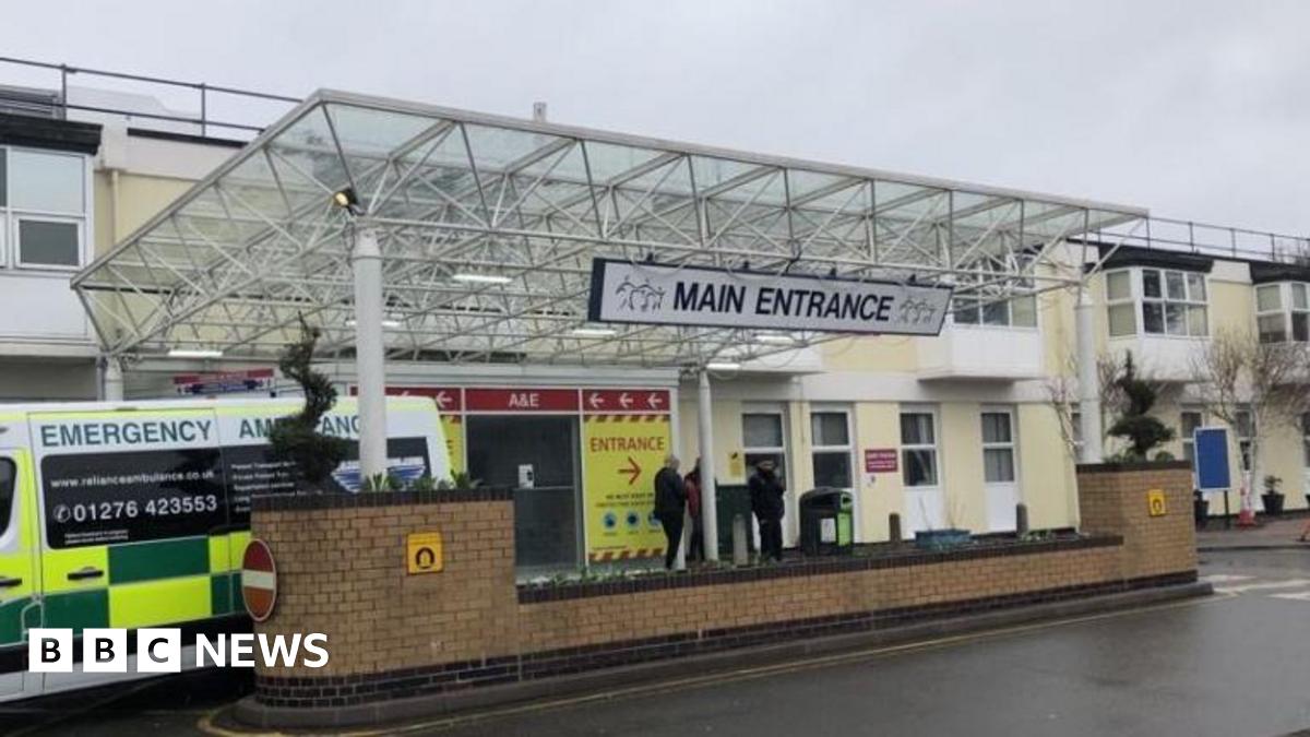 The main entrance to a hospital A&E department with an ambulance parked outside