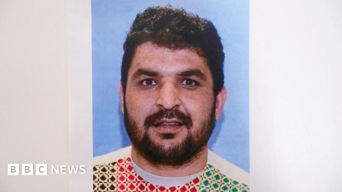 Young 18 year old man sits in the passenger seat of a black VW car, his arm resting on the open window as he looks to camera