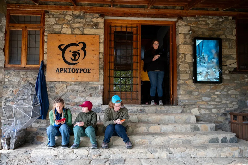 Visitors sit on the stairs inside the Arcturos bear sanctuary in Nymfaio (AP)