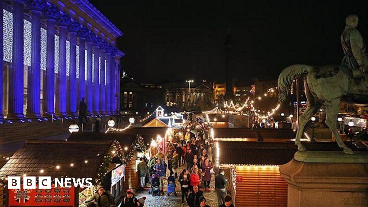 Liverpool Christmas Market at night showing traditional wooden chalets lit up on St George's Plateau with St George's Hall lit up with white lights.