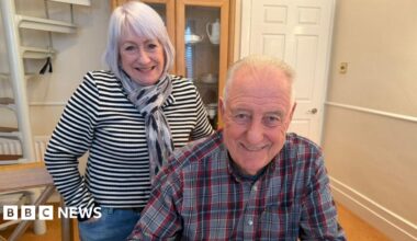 Young 18 year old man sits in the passenger seat of a black VW car, his arm resting on the open window as he looks to camera