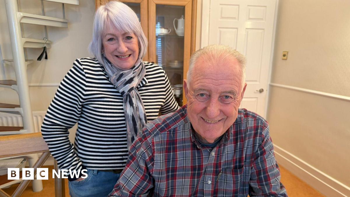 Young 18 year old man sits in the passenger seat of a black VW car, his arm resting on the open window as he looks to camera