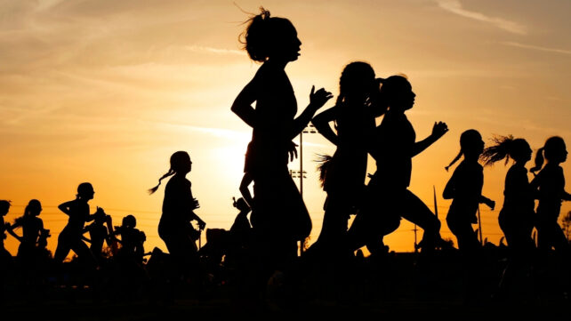 Silhouettes of many people running at sunset