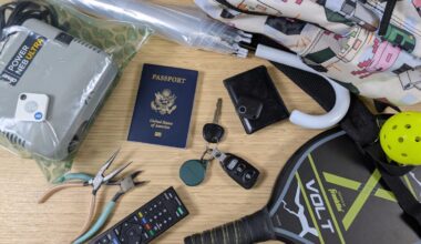 bluetooth trackers and various trackable items on bamboo desk including a passport, car keys, and umbrella