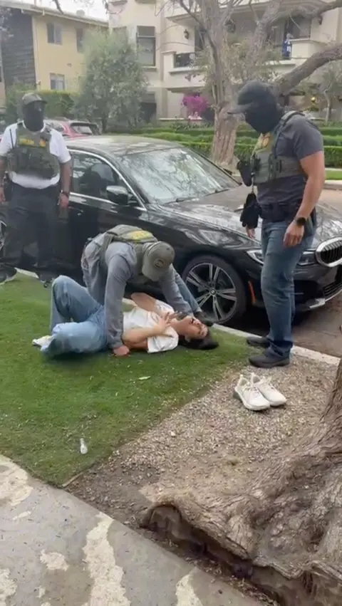 Submitted photo Marjan lies on ground on her front lawn while immigration officers stand by and offer assistance