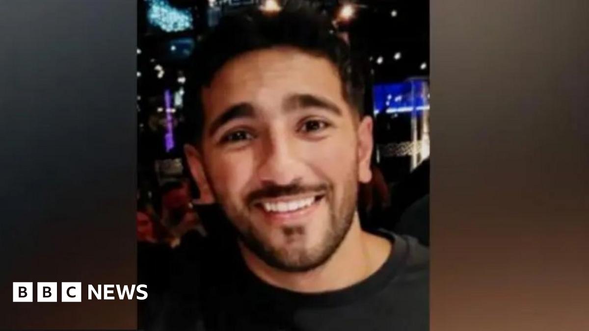 Image of Rehaan smiling at the camera. He is wearing a black t-shirt. Behind him a nightclub can be seen.