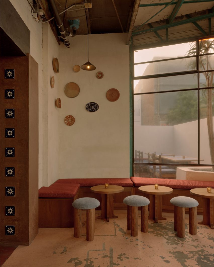 Bench seating and stools below a wall display of ceramic plates