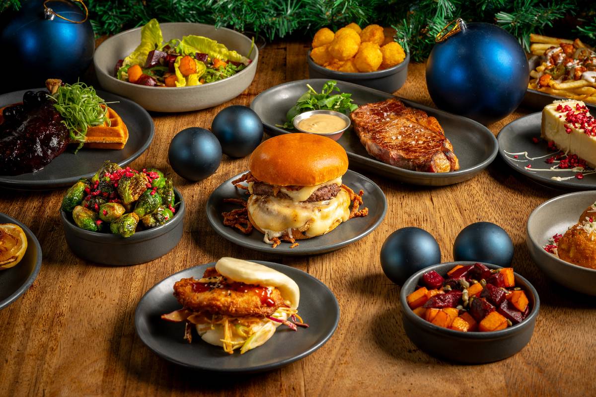 a table full of festive food including burgers and potatoes with baubles between the plates
