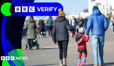 Young 18 year old man sits in the passenger seat of a black VW car, his arm resting on the open window as he looks to camera