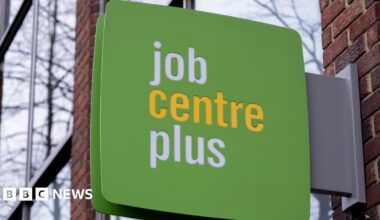 A green sign hangs outside a Job Centre Plus office.