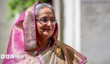 Sheikh Hasina is pictured looking to her left slightly smiling, in a pink and green head dress.