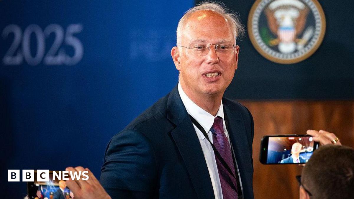 Kirill Dmitriev in a blue jacket poses for photographers in Alaska with whispy silver hair and transparent glasses