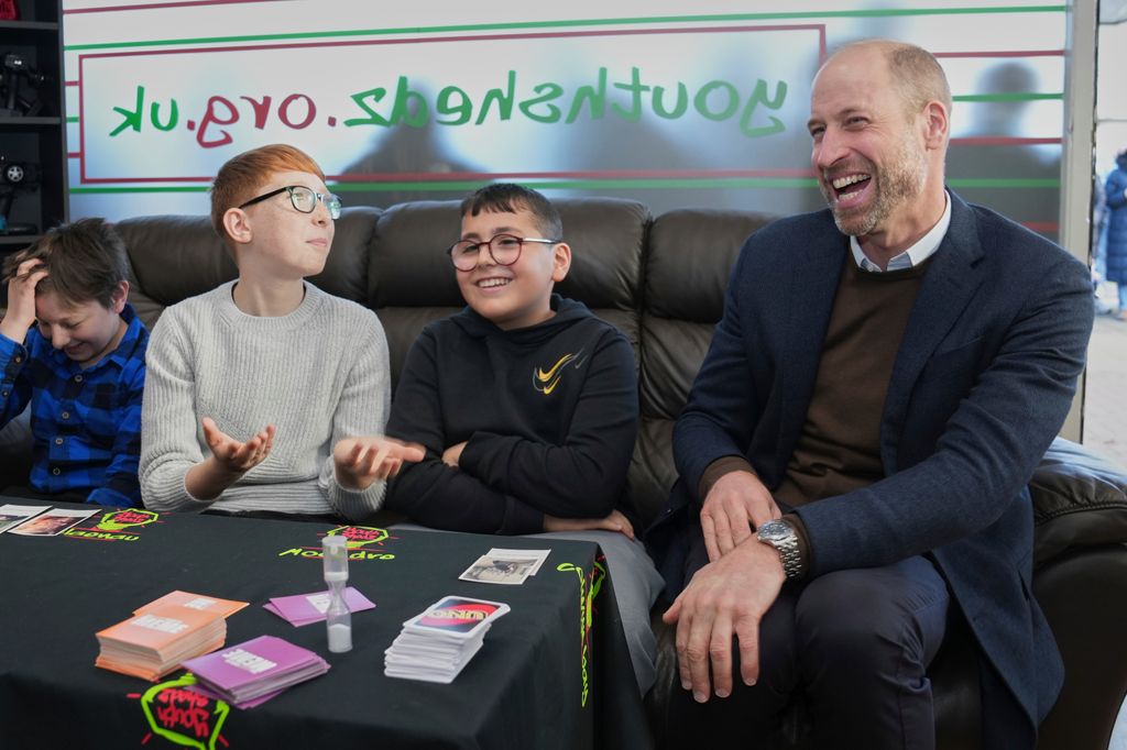 The Prince of Wales laughing sitting on sofa with two young boys
