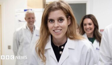 Princess Beatrice during a visit to Borne's laboratories. She is wearing a lab coat and smiling at the camera