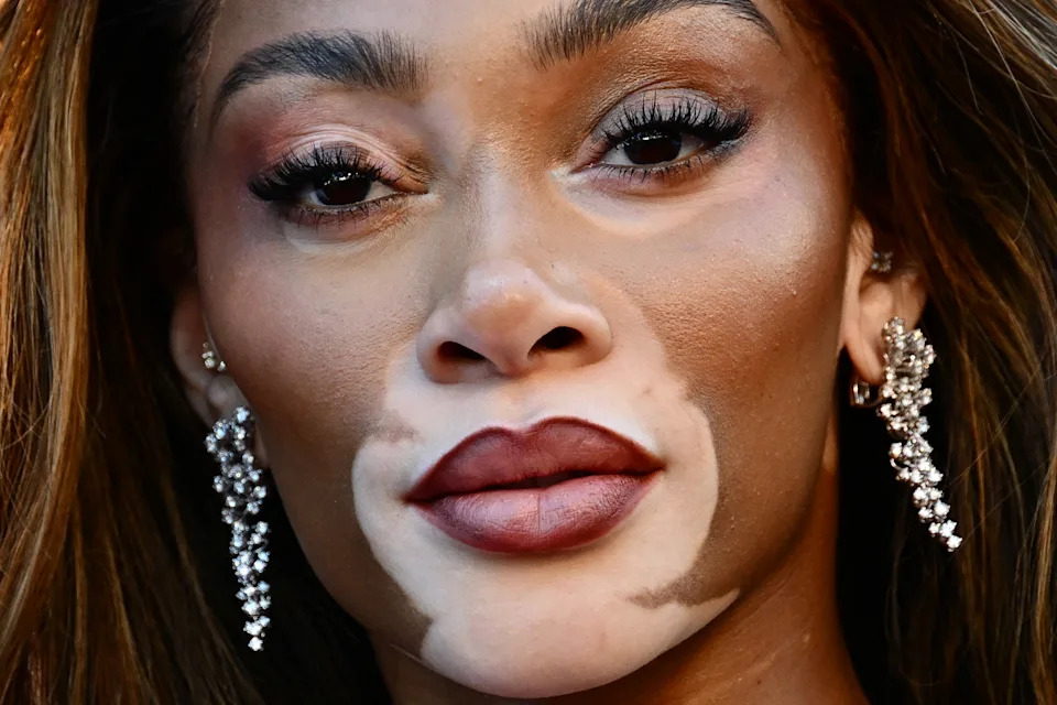 Winnie Harlow close up, wearing sparkling earrings and dramatic eye makeup