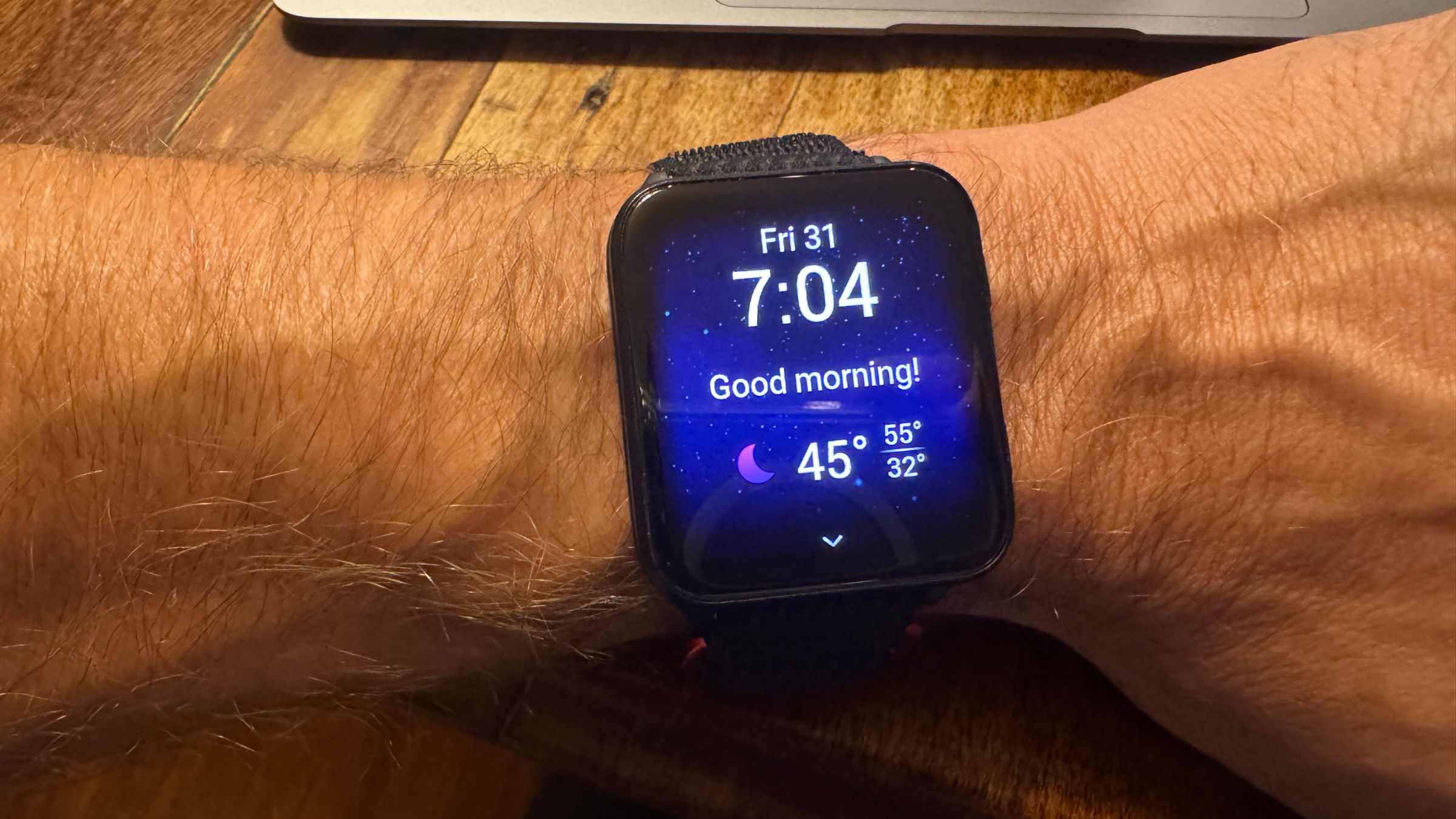 Garmin Venu X1 displaying time and good morning message on man's wrist at desk