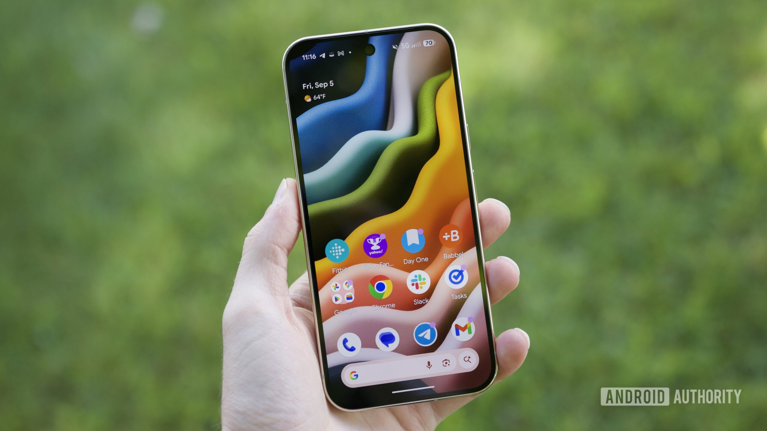 Someone holding the Google Pixel 10 Pro with its screen on, showing the home screen.