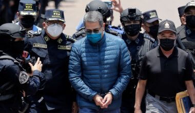 Juan Orlando Hernandez, wearing handcuffs and a blue jacket, is escorted by police special forces officers in Tegucigalpa