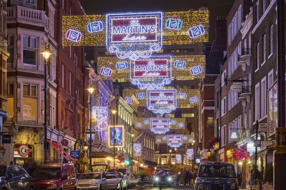 banner shaped christmas lights stretching from building to building above st martins lane at night