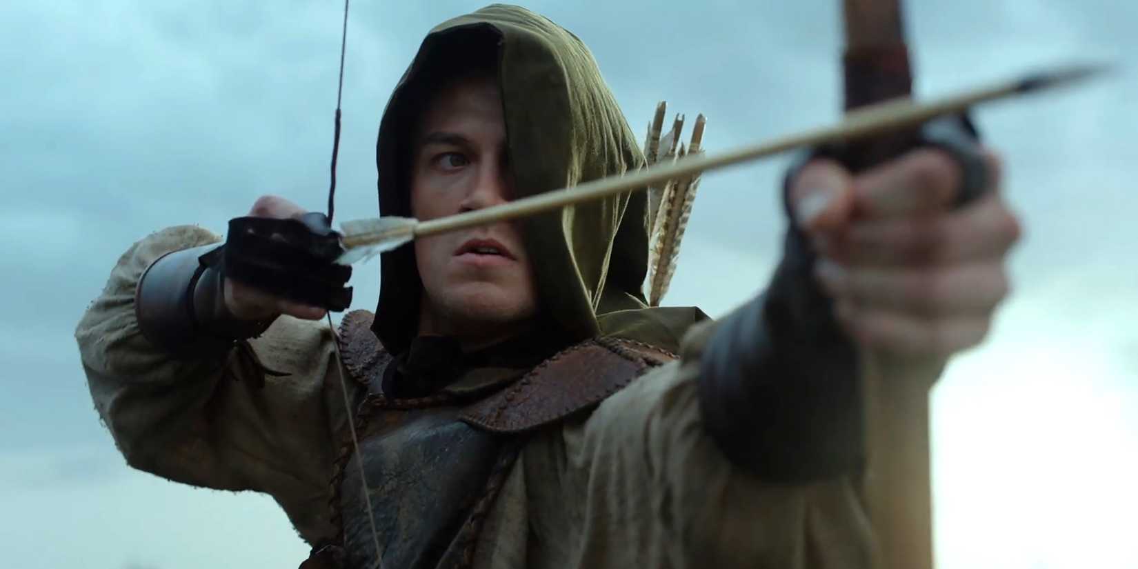 Jack Patten as Rob drawing an arrow while his face in covered in a hood in Robin Hood